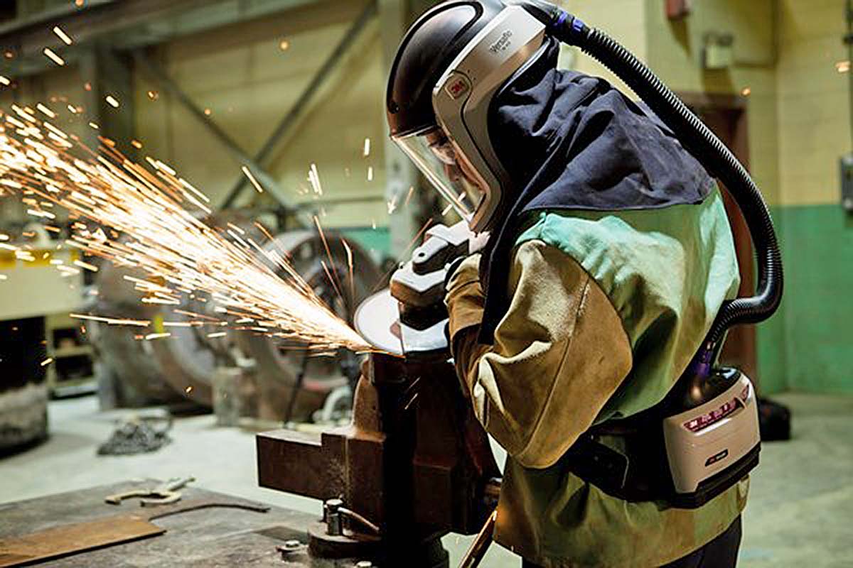 Cutting metal in protective gear and mask.