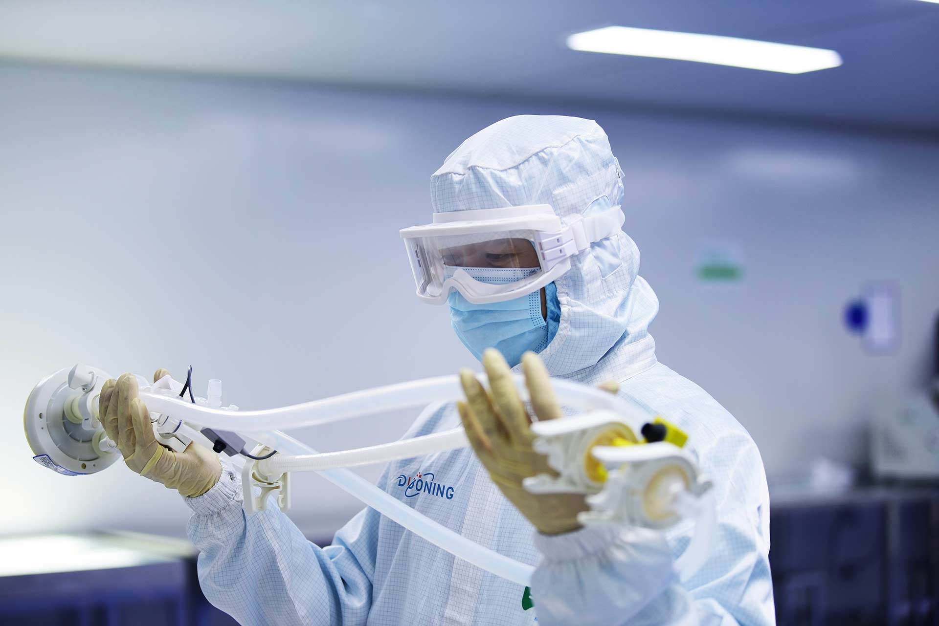In a medical facility inspecting equipment wearing protective suit, goggles and mask.