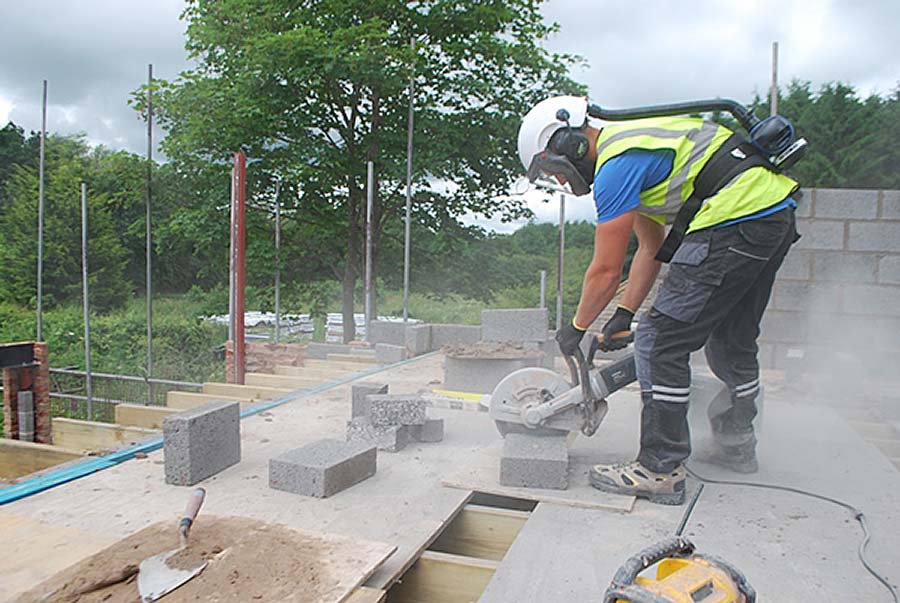 Cutting concrete on a construction site wearing respiratory equipment