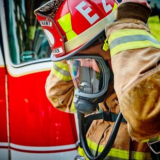 Fireman wearing safety equipment, visor and breathing tube.